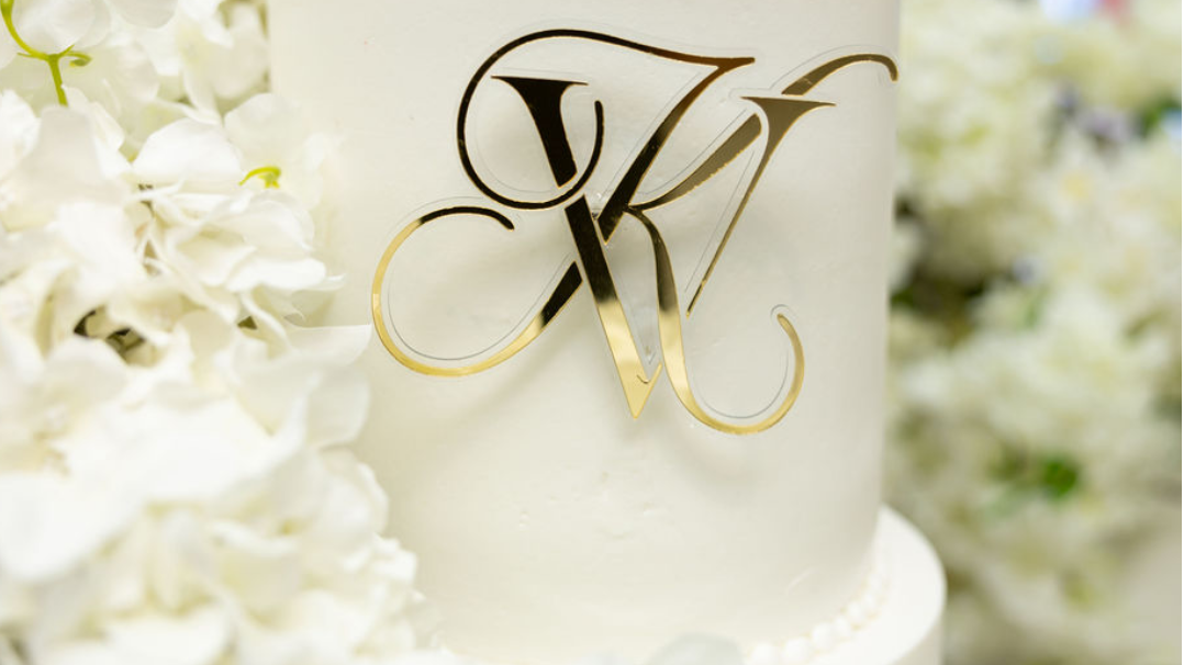 White wedding cake with gold monogram cake charm