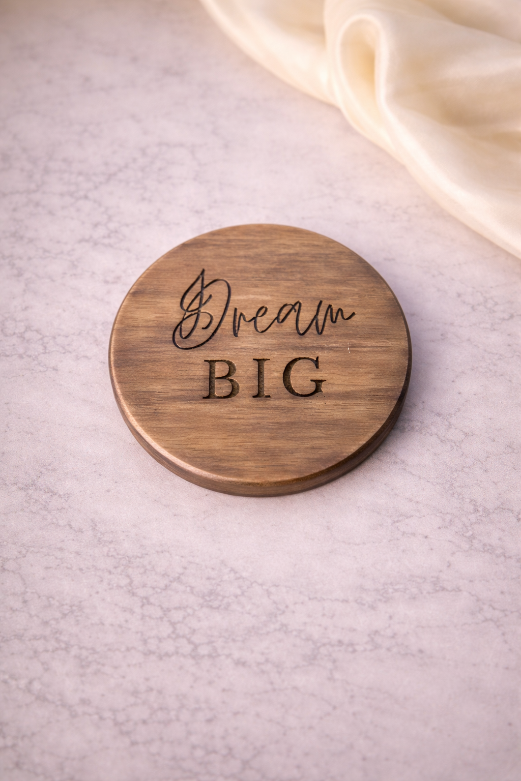 Wooden coaster with 'Dream BIG' engraving on a light background