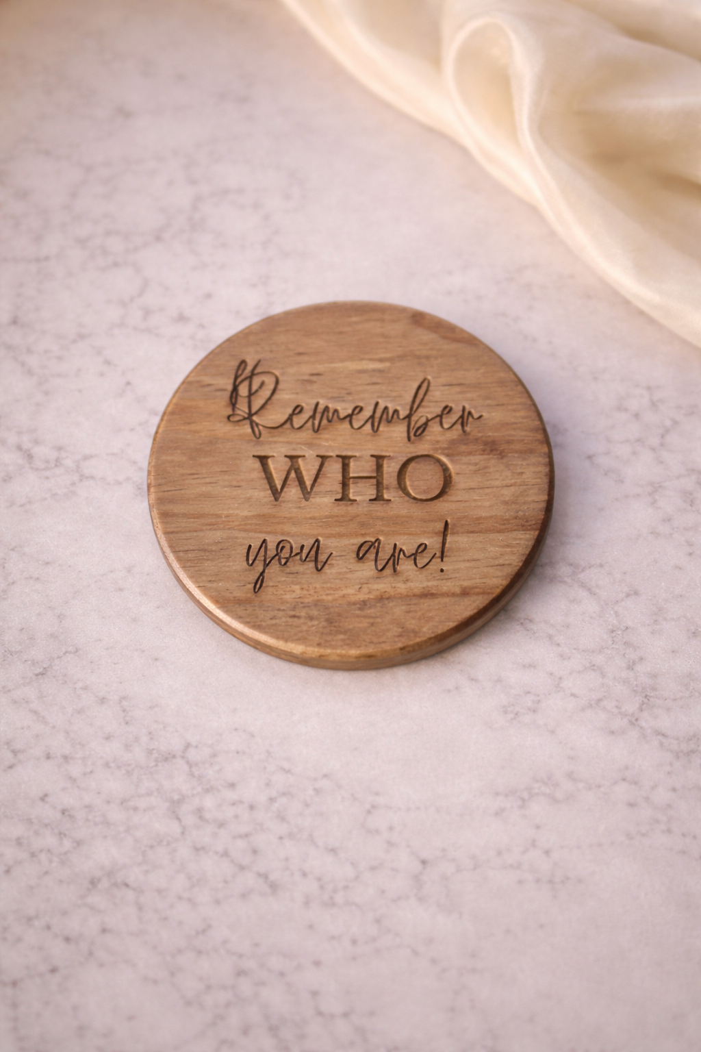 Wooden coaster with engraved text on a light background